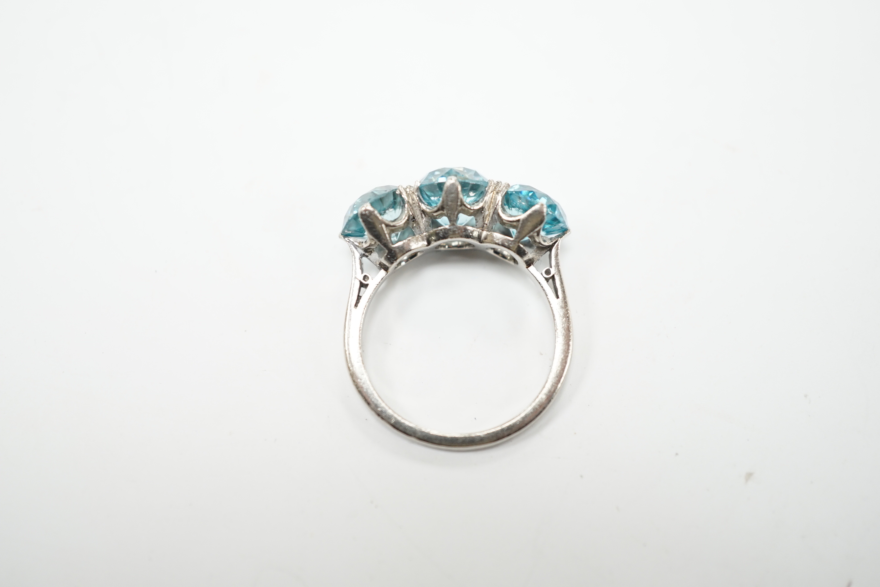 A white metal and three stone blue zircon set dress ring, size L, gross weight 4.1 grams.